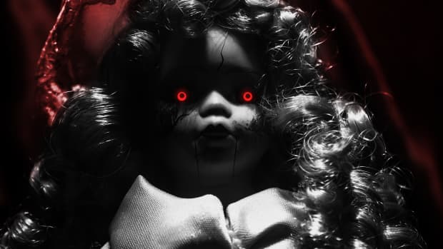 Scary demon possessed plastic doll with glowing red eyes on dark background.