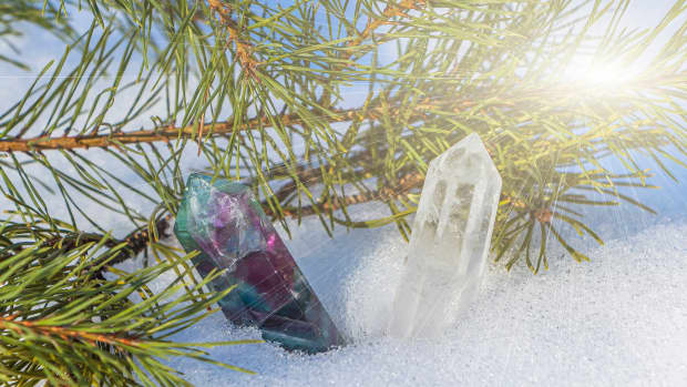 Fluorite and quartz crystal on snow among spruce branches.