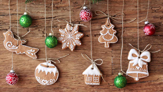 Gingerbread cookies hanging over wooden background dangling from pine boughs.