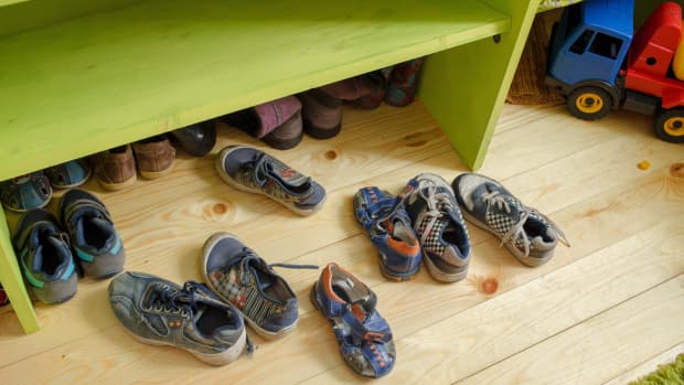 children's shoes scattered on a floor beneath a green cubby