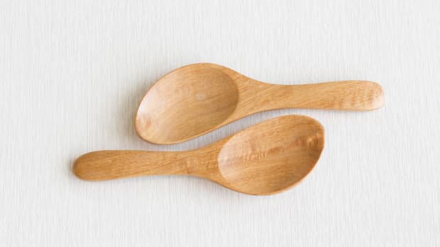 Two identical wooden spatulas on a white tablecloth.