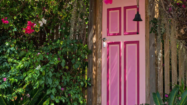 A pink door leading to nowhere is surrounded by brightly blooming pink flowers.