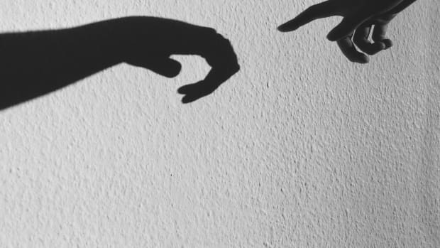 Two shadows of hands reach towards each other.