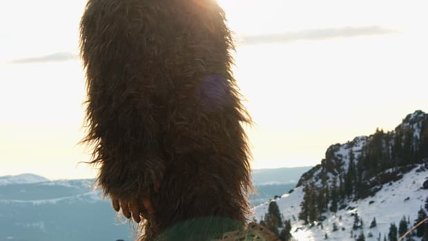 A bigfoot sasquatch creature strolling along a snowy mountain top.