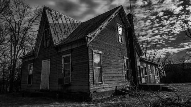 black and white photo of a creepy old abandoned farmhouse