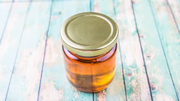 a small capped mason jar of amber liquid on a rustic blue painted plank table.