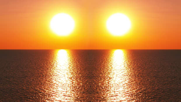 two suns side by side setting over a body of water