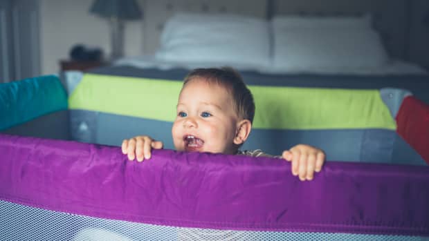 Baby shouting happily over the top of a playpen