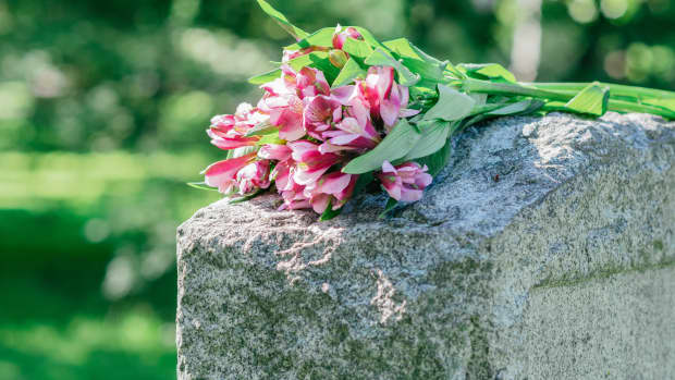 Pink bouquet of lowers laid across a gravestone
