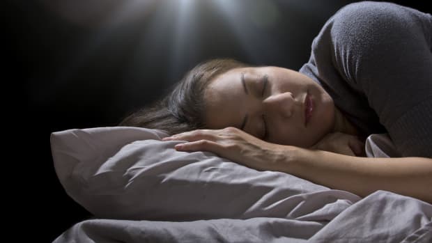 a woman asleep in bed with a bright light shining over her head