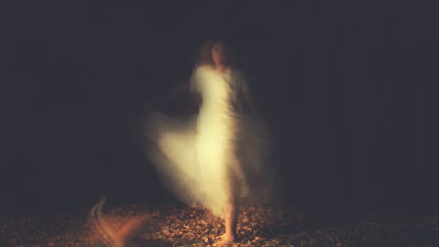 Ghostly image of a woman dancing on leaves at night.