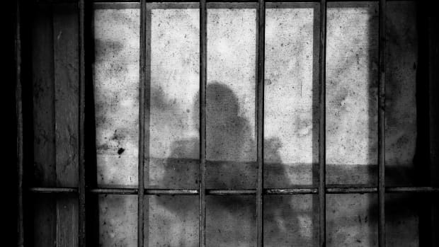 a shadowy figure behind bars