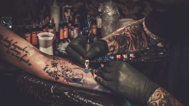 Professional tattoo artist making a tattoo on a young woman's arm.