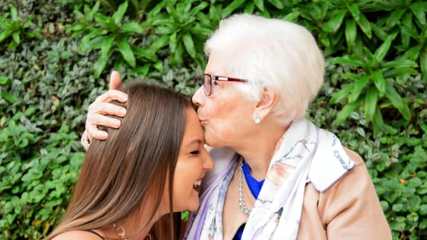 an old woman kisses a younger woman on the forehead