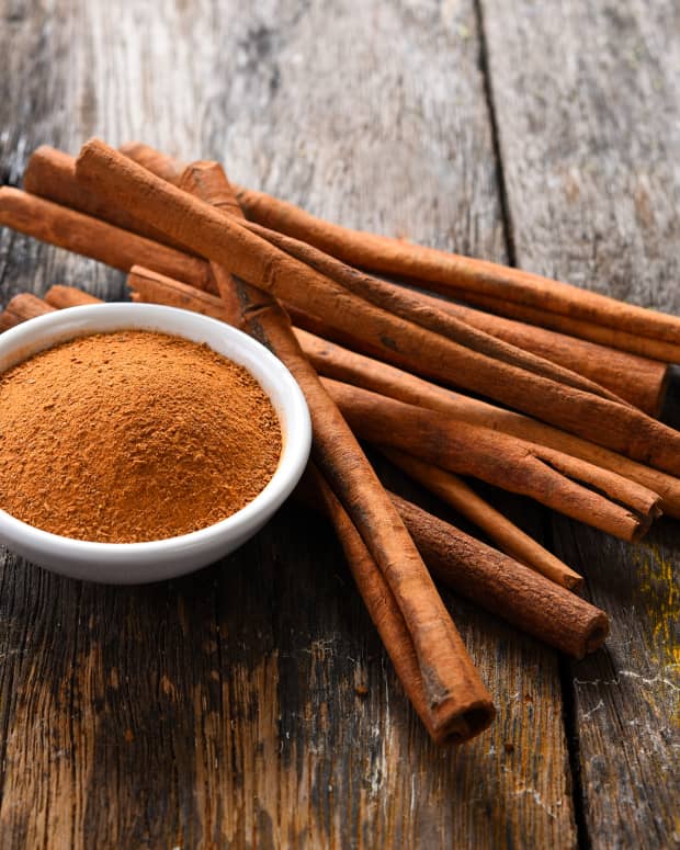 Cinnamon sticks and a bowl of powdered cinnamon on a wooden table