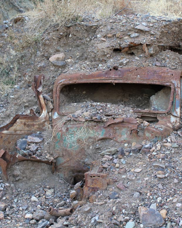 a rusted car is buried in rubble