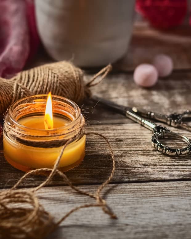 a candle and some twine and scissors on a wooden table