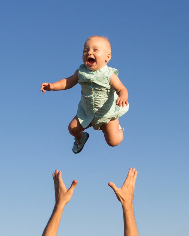 a baby flies in the air with an adults hands reaching up from beneath