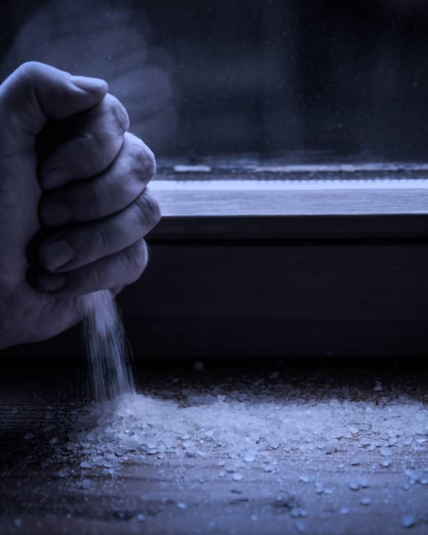 Hand strewing salt on a windowsill