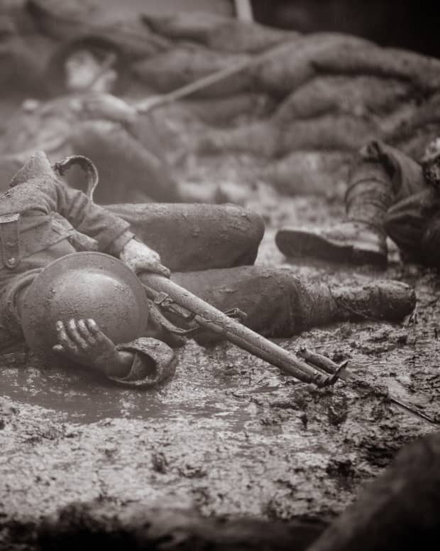 sepia tones photo of a fallen WW1 soldier clutching his rifle and trench helmet