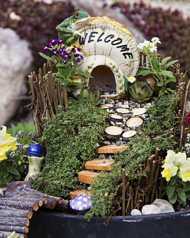 A little welcome sign set up over a tiny fairy garden