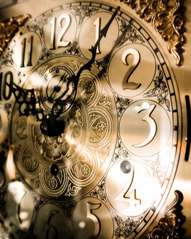A close up shot on the ornate golden face of a grandfather clock