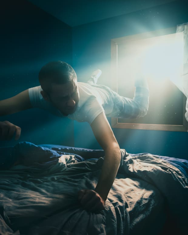 a man is pulled off his bed and through the air toward a bright light shining in his bedroom window