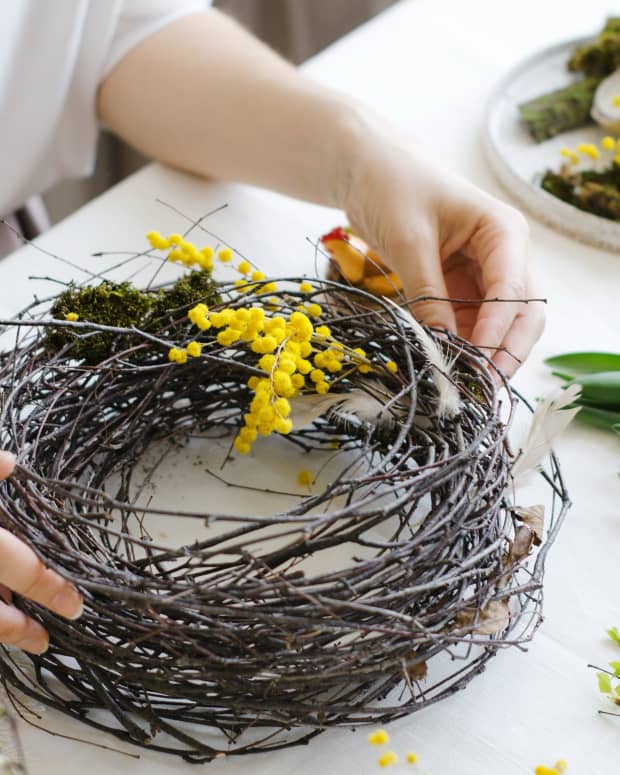 a woman's hands forming a wreath out of willow and flowers.
