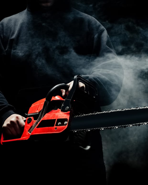 chainsaw being wielded in the hands of a shadowy figure surrounded by smoke and mist.