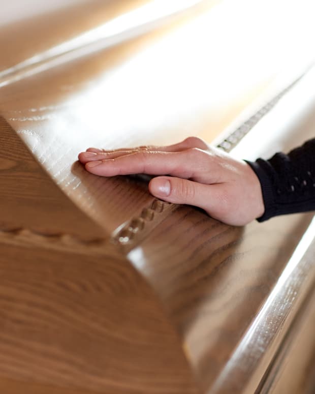 A woman's hand caresses a casket.
