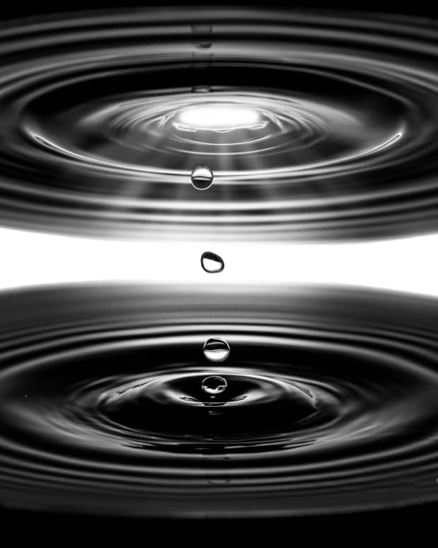 A black and white photo of a water droplet seemingly traveling up and down at the exact same time.