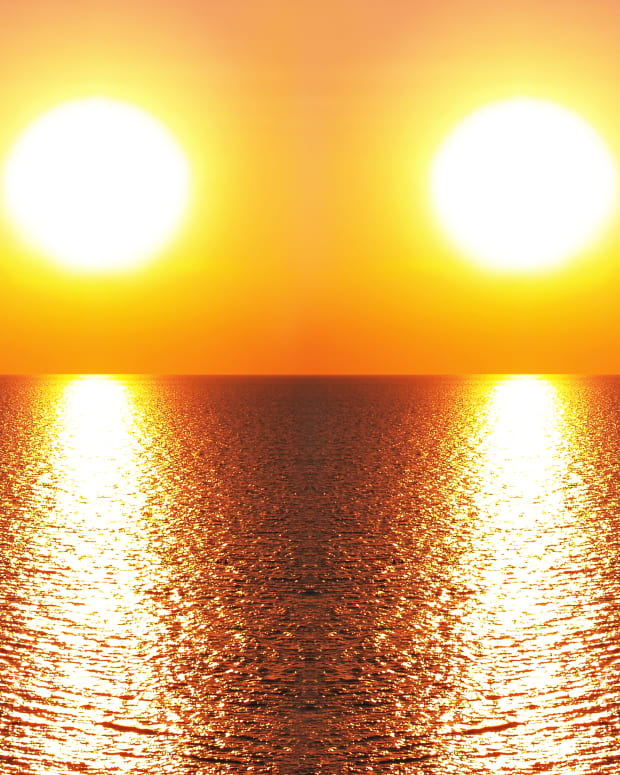 two suns side by side setting over a body of water