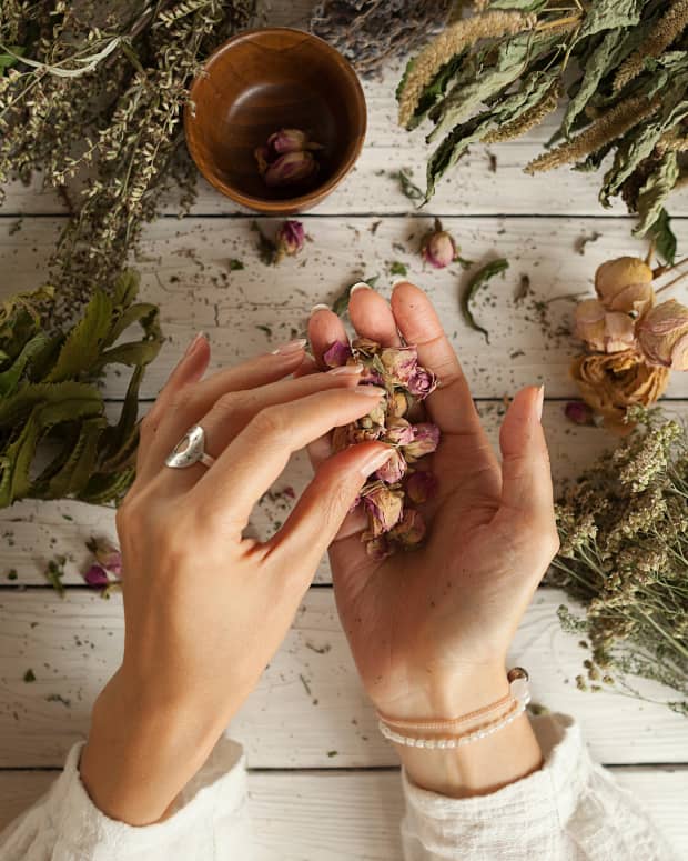 shot from above, a woman's hands working with herbs above a rough-hewn table.