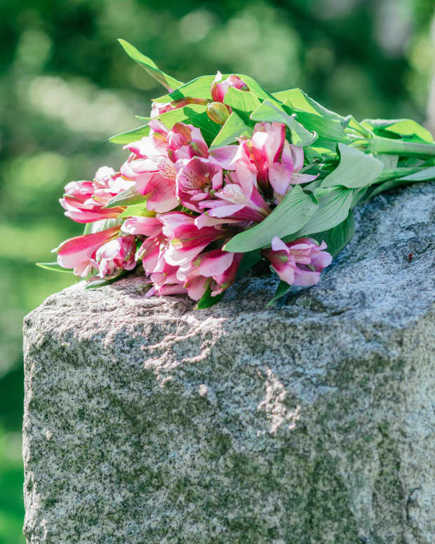 Pink bouquet of lowers laid across a gravestone