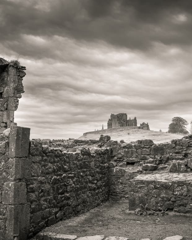 a black and white view of castle ruins under a stormy sky