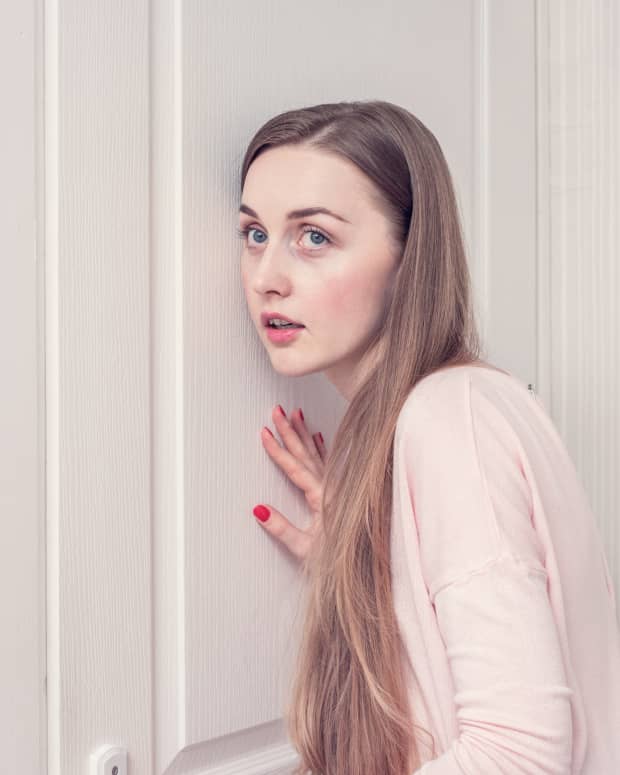 a young white woman is listening at a door.