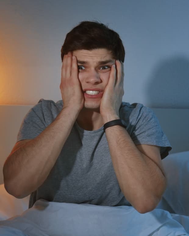 a young man is sitting up in bed looking scared