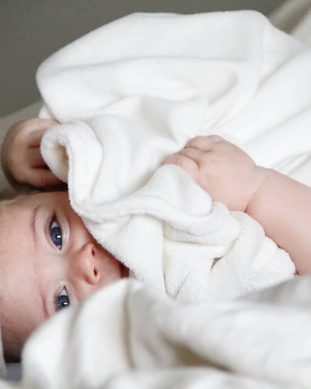 a baby looks out from under a towel