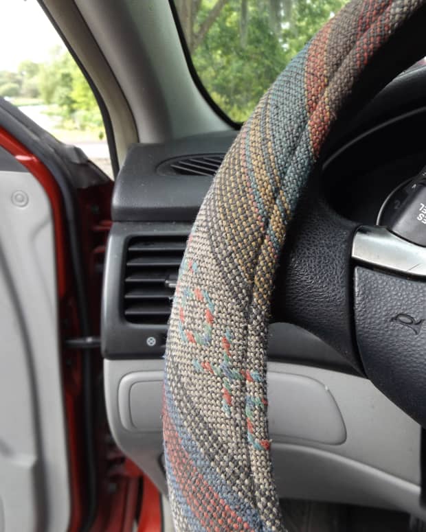 a close up on a colorful woven steering wheel cover on a car.