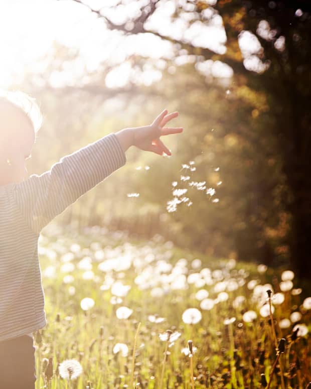 a small boy dances in a field covered in a glare of a light