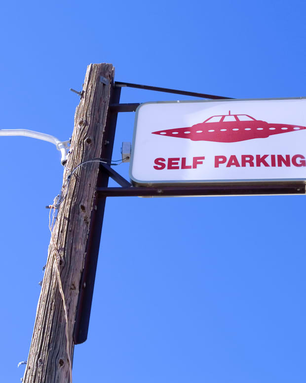 a "self parking" sign with a flying saucer on it appears at the top of a lamp post.