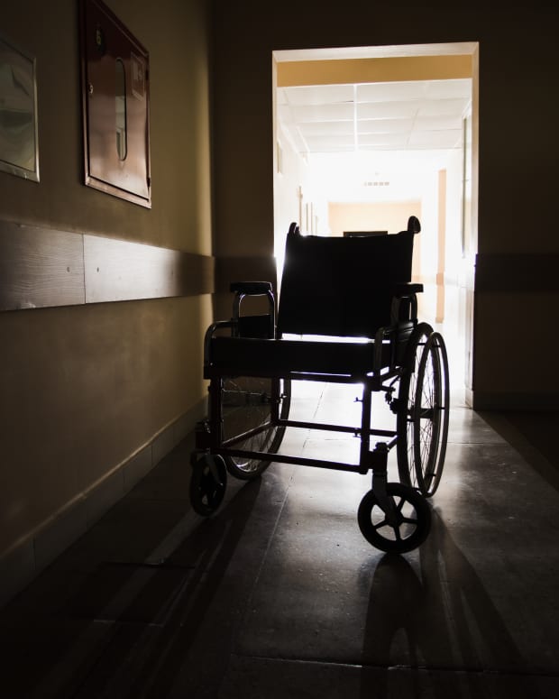 Creepy empty wheelchair in a dark hospital hallway.