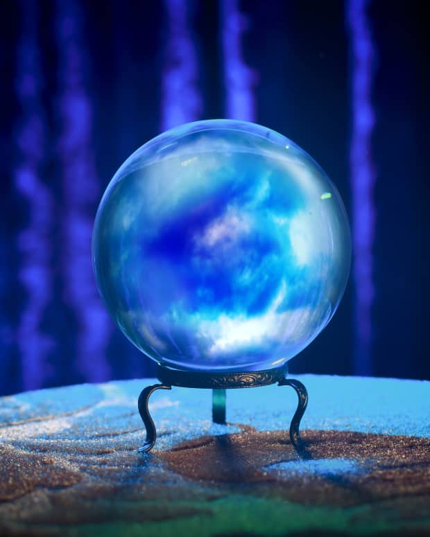 a crystal ball glows blue and purple on a pedestal