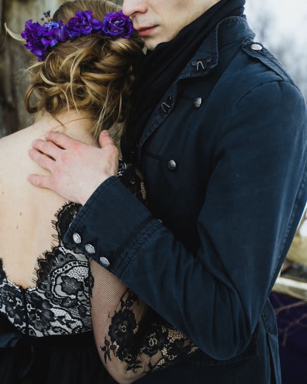 a couple in gothic Victorian wear embrace in a snowy field