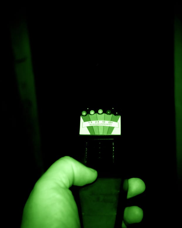 a glowing green ghost hunting gadget in a dark room
