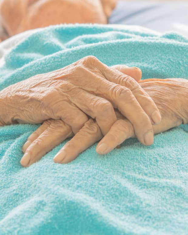 old woman's hands folded on a hospital blanket