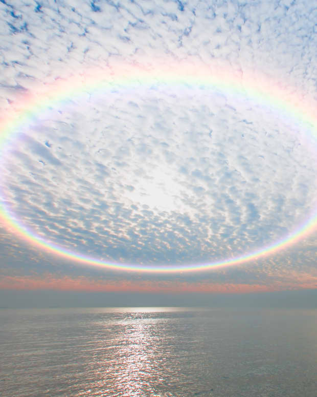 a rainbow ring in the sky over water