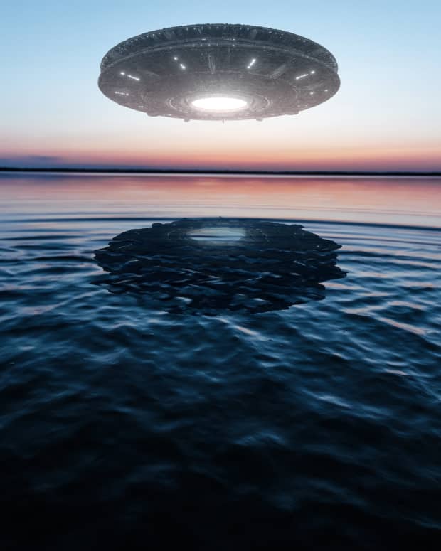 A UFO hovering above a body of water at sunset.