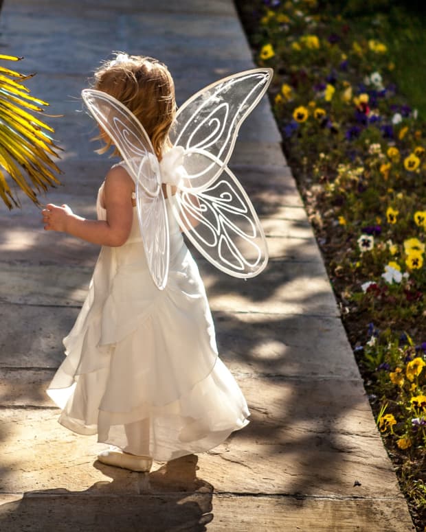 a little girl in a fairy costume walks down a flowered path